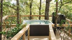 a hot tub sitting on top of a wooden deck in the woods next to trees