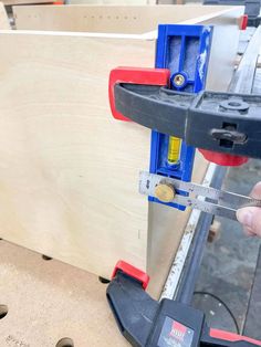 a person holding a pair of scissors in front of a piece of wood that is being worked on