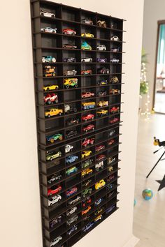 the toy cars are lined up on the black shelving unit in the living room