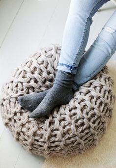 a woman is sitting on a bean bag chair with her legs crossed and wearing high heels