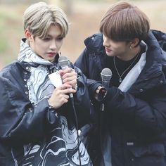 two young men standing next to each other holding microphones