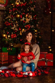 a woman and child sitting in front of a christmas tree