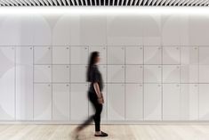 a woman standing in front of a white wall with lots of lockers on it