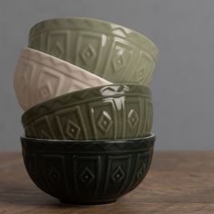 three green and white bowls sitting on top of a wooden table next to each other