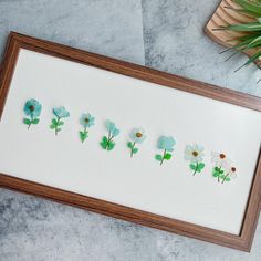 some flowers are arranged in the shape of letters on a white paper and wooden frame