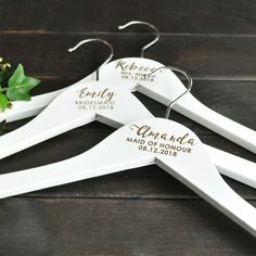 three personalized wedding hangers with names on them and flowers in the bottom right corner