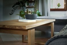 a wooden table sitting in front of a couch next to a potted green plant