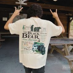 a man standing in front of a picnic table holding his hands up to the side