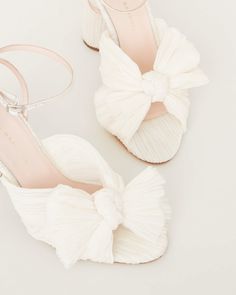 a pair of white shoes with bows on the toes and heels are sitting next to each other