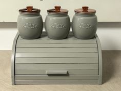 three gray jars sitting on top of a counter