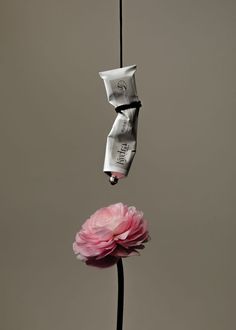 a pink flower is hanging upside down on a black pole with two packets attached to it