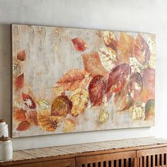 a large painting hanging on the wall above a wooden cabinet in a room with white walls