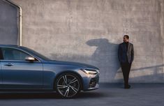 a man standing next to a car in front of a wall