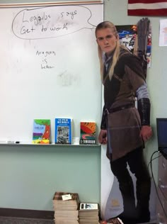 a woman dressed in costume standing next to a whiteboard with writing on it and books