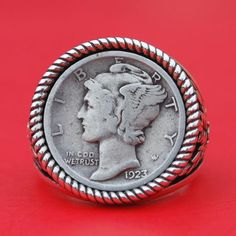 an old silver coin is sitting on a red surface with a rope around the edge