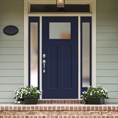 a blue front door with two planters on the steps and a light above it