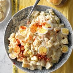 a bowl filled with potato salad on top of a table next to other bowls and utensils