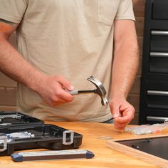 a man holding a pair of pliers in his hands while working on a piece of wood