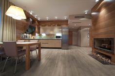 a kitchen and dining area with wood flooring, white walls and ceiling lighting is shown