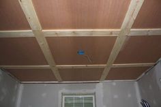 an unfinished room with wood paneling on the ceiling and a window in the corner