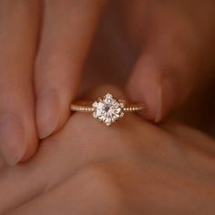 a woman's hand holding an engagement ring with a diamond on the middle finger