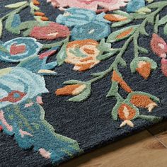 a blue rug with flowers and leaves on the floor next to a wood flooring board