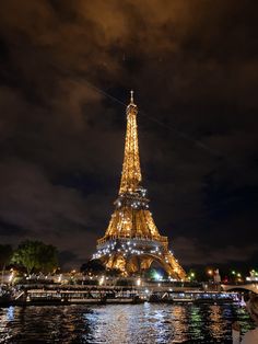 the eiffel tower lit up at night with lights reflecting in the water below