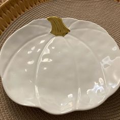 a white plate with a gold leaf on it sitting on a woven place mat next to a basket