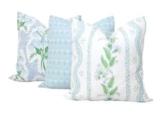 three blue and white pillows with green floral designs on them, one in the middle