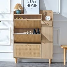 a wooden cabinet with baskets on top and a poster above it that says stay home