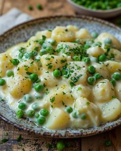 a bowl filled with pasta and peas on top of a wooden table