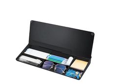 an open black case with sunglasses, pens and other items in it on a white background