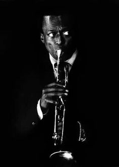 a man playing a trumpet in the dark