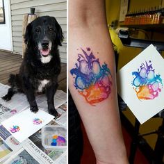 a dog is sitting on the floor and next to a tattoo that has watercolor splashes on it