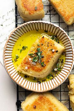 some food is in a bowl on a cooling rack and next to it are bread