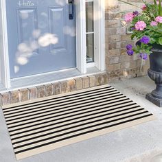 a black and white door mat sitting next to a blue front door