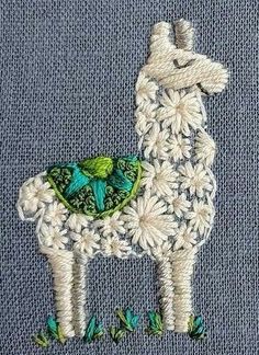 a close up of a llama on a piece of cloth with green and blue flowers