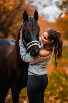 a woman is hugging her horse in the fall