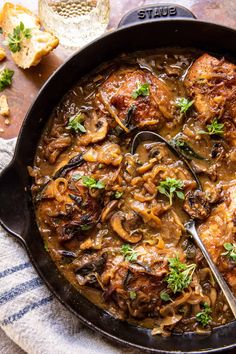 a skillet filled with meat and mushrooms covered in gravy, garnished with parsley