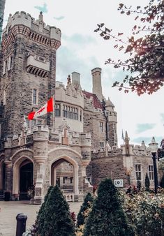 an old castle with a canadian flag on it's front door and trees in the foreground