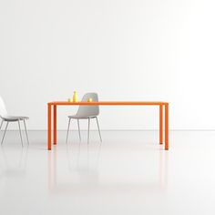 an orange table and two white chairs are in front of a white wall with a light on it