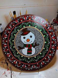 a snowman painted on top of a plate with paintbrushes in the background