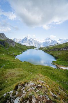 a large body of water sitting on top of a lush green hillside covered in grass