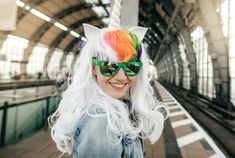 a woman with long white hair wearing sunglasses and a cat ears headdress at a train station