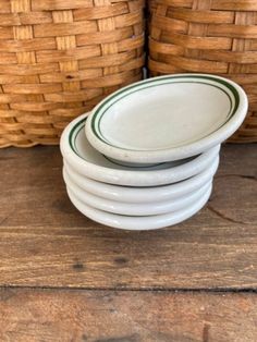 stack of white plates sitting on top of a wooden table next to wicker baskets