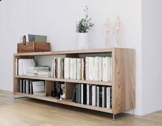 a bookshelf with many books on top of it in front of a white wall