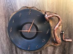 a clock made out of an old vinyl record with copper fittings on the sides