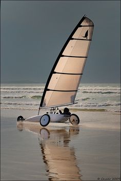 a sailboat on the beach with waves in the background