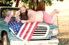 a man laying on top of a truck with an american flag