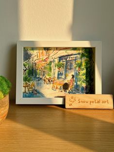 a potted plant sitting on top of a wooden table next to a framed painting